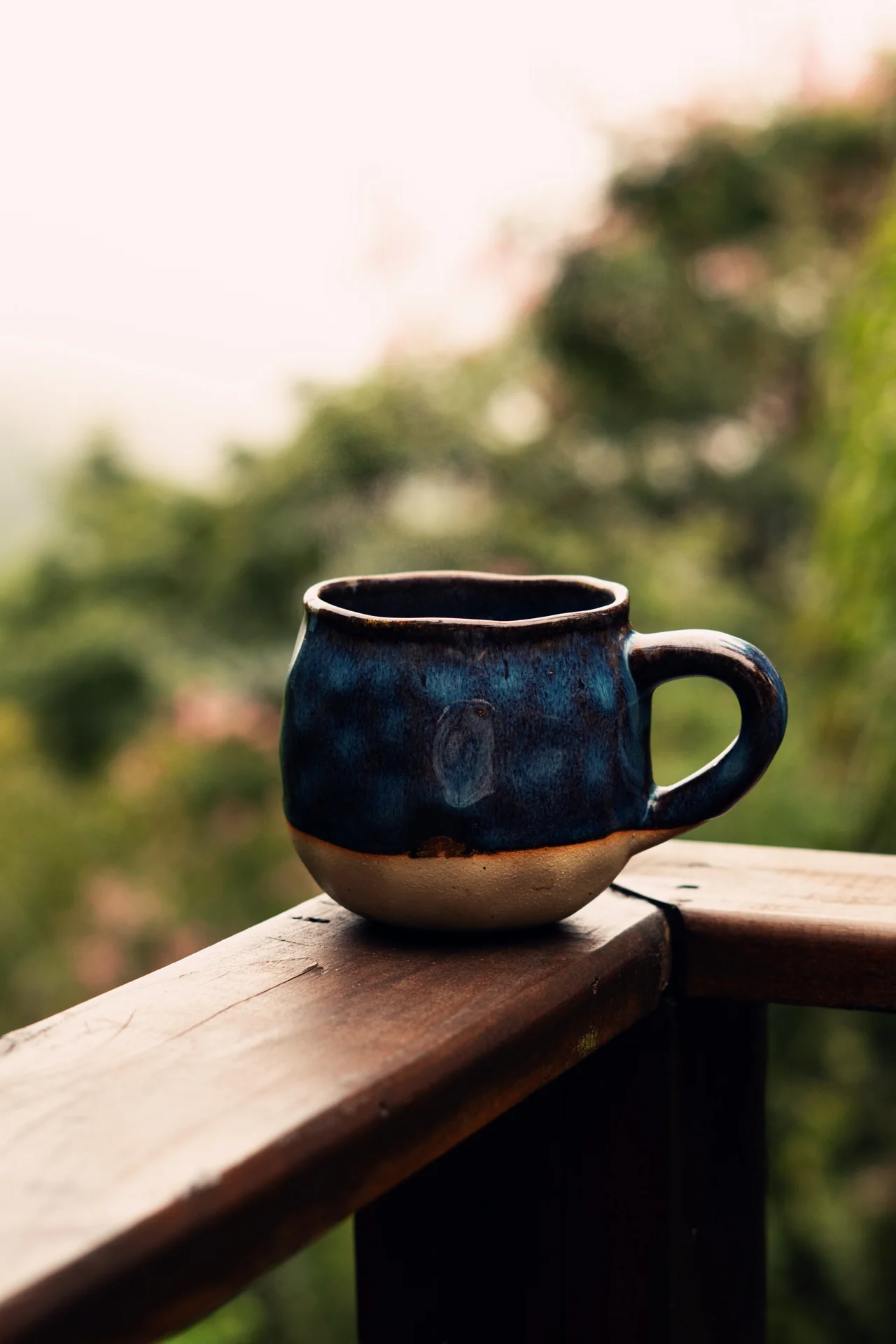 Xícara de café sobre a madeira, com a paisagem da serra ao fundo