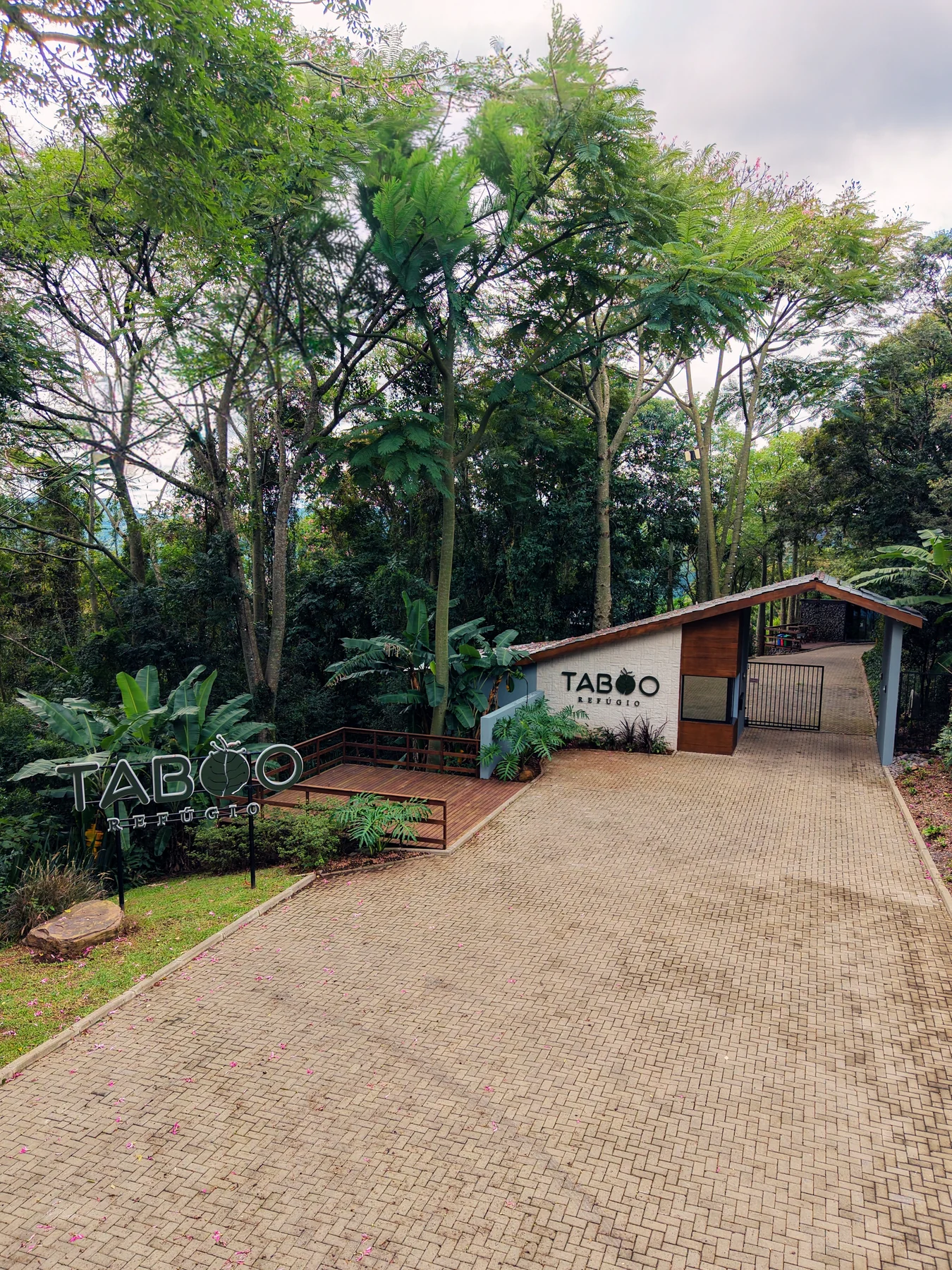 Fachada e entrada do Taboo Refúgio, com o letreiro do hotel entre as árvores